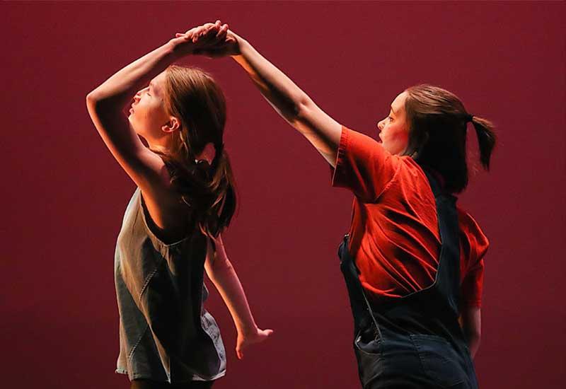 one student twirls another on stage during a dance recital